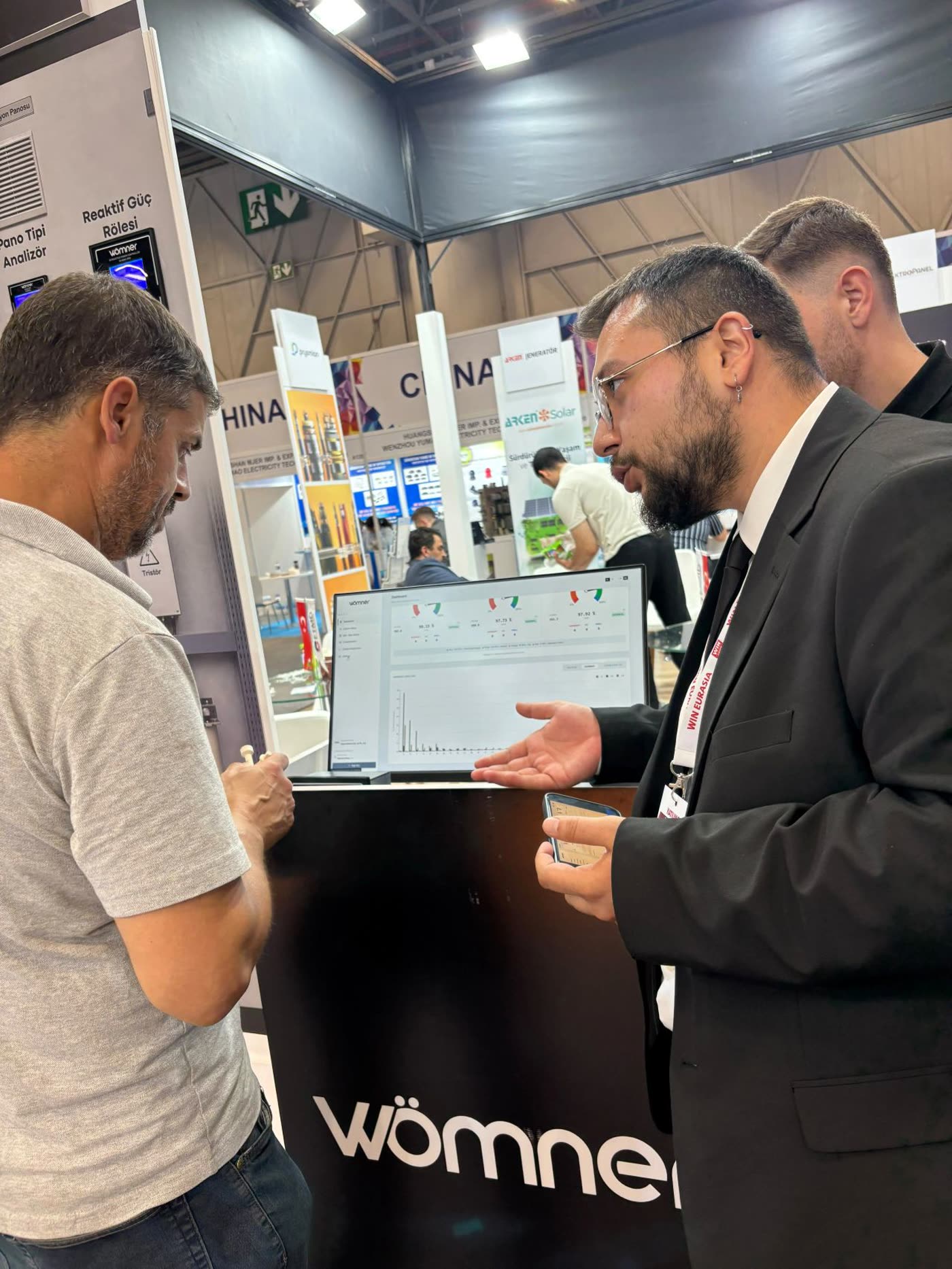 Mertcan Çakır walking a visitor through the Wömner dashboard at WIN Eurasia